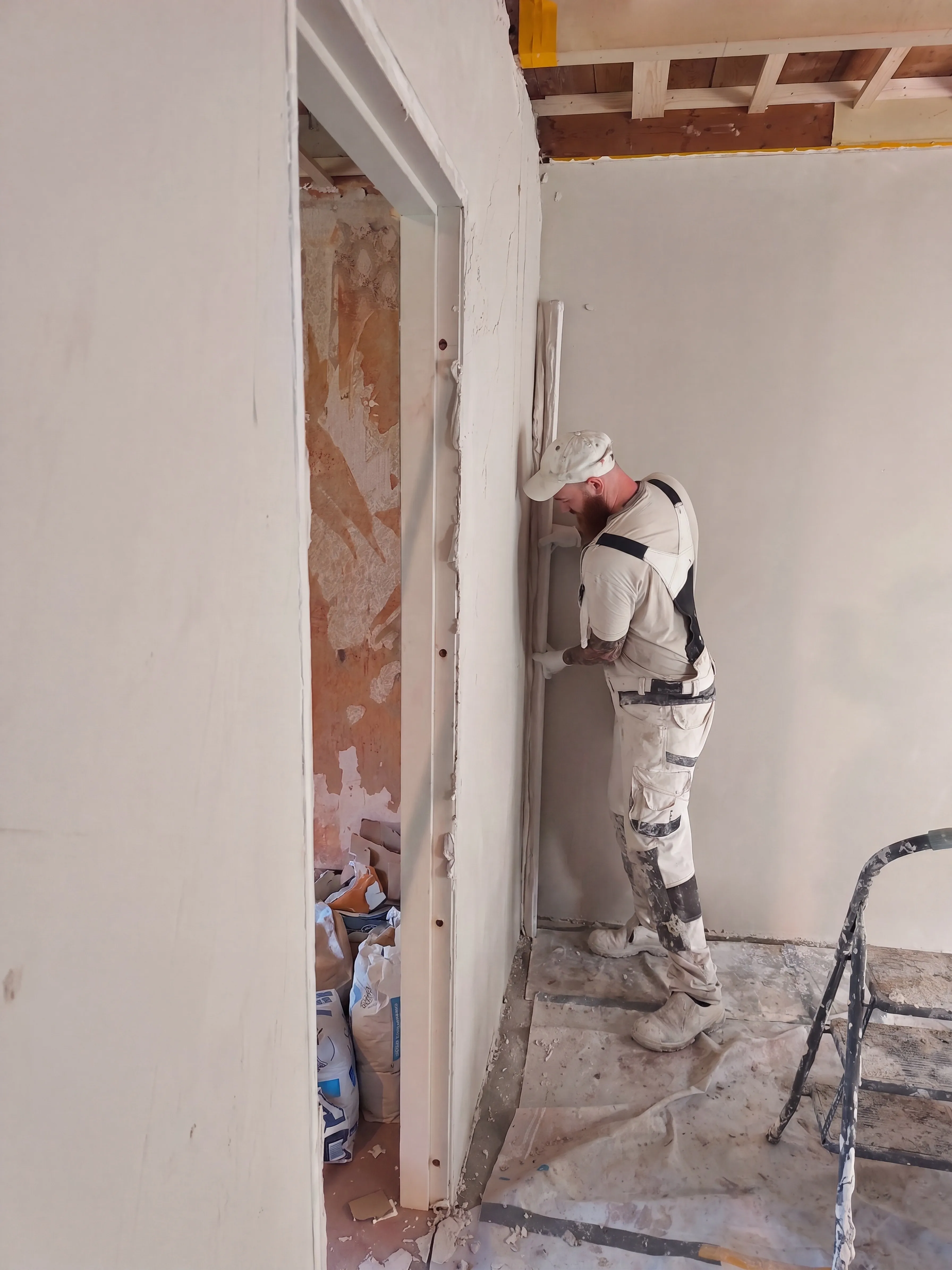 stukadoor brengt stucwerk aan naast een deurkozijn